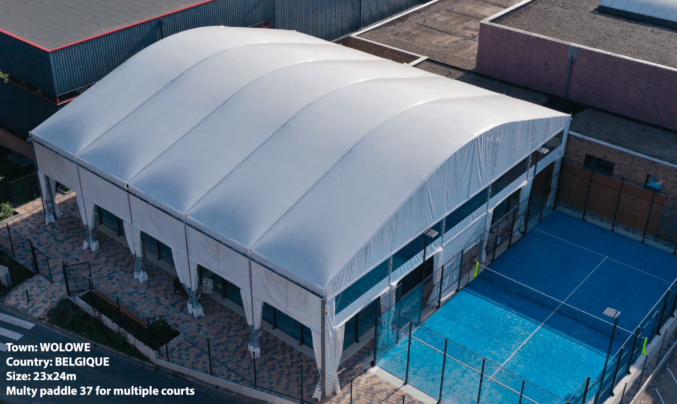 Aerial view of a white arched fabric structure covering padel courts in Wolowe, Belgium.